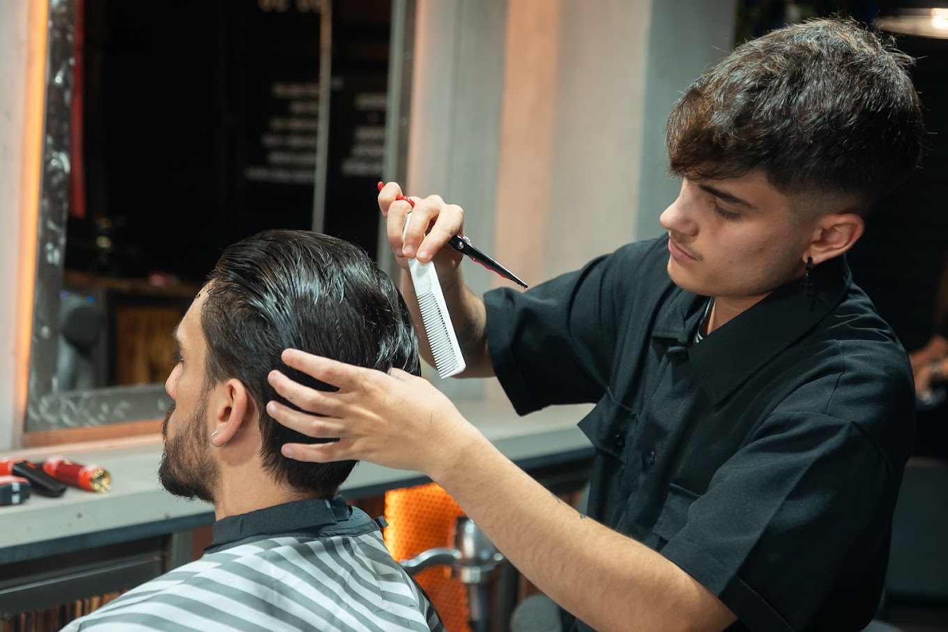 Barbero peinando y cortando el cabello de un cliente en The Original Barber Shop.