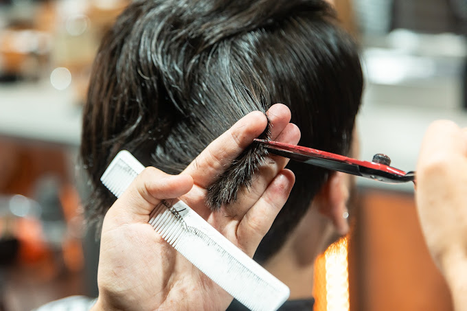 Primer plano de un corte de cabello en The Original Barber Shop, con tijeras y peine.