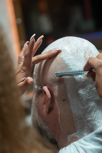 Barbera realizando un afeitado clásico de cabeza con navaja en The Original Barber Shop.