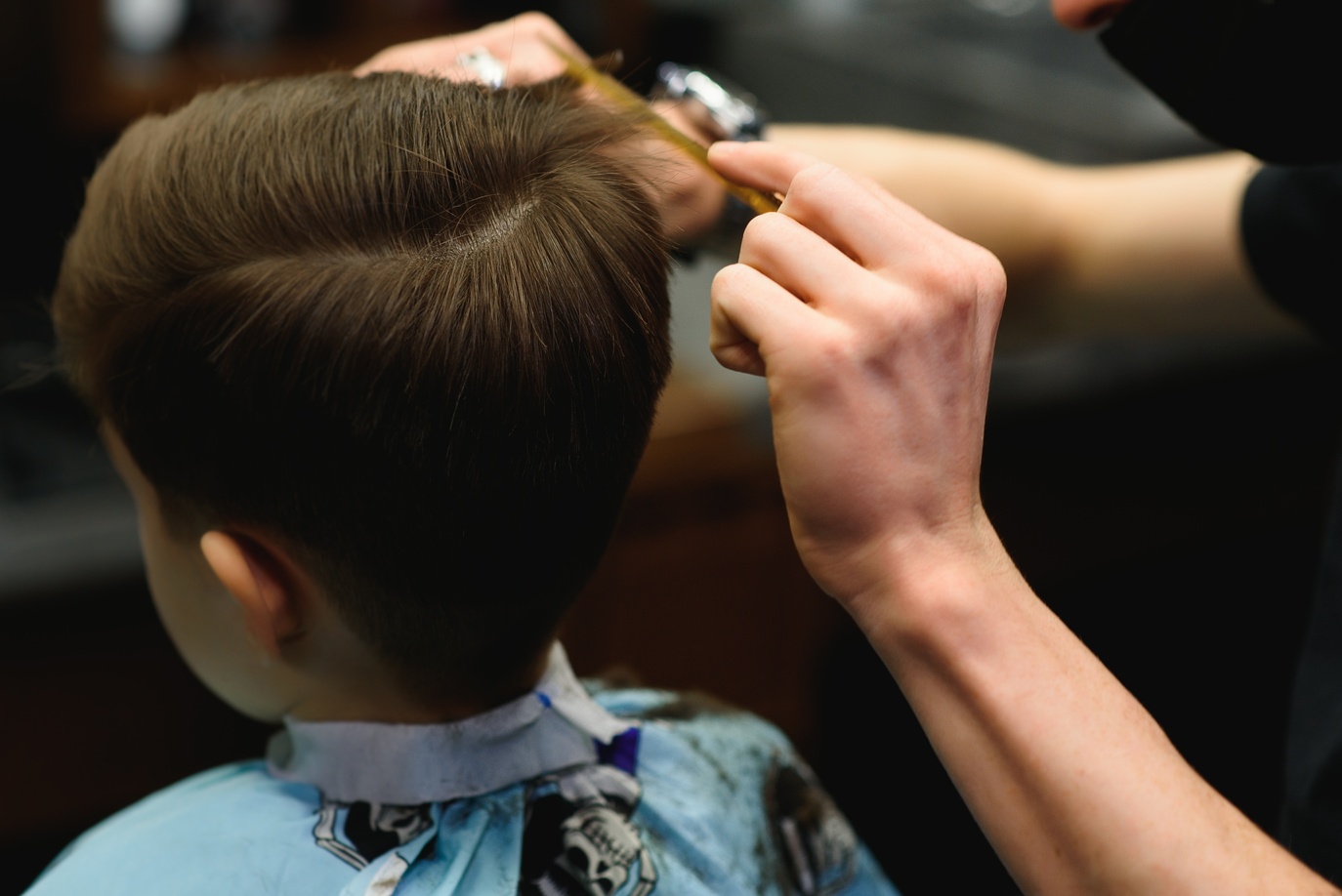 Un barbero realizando un corte de cabello a un niño en The Original Barber Shop.