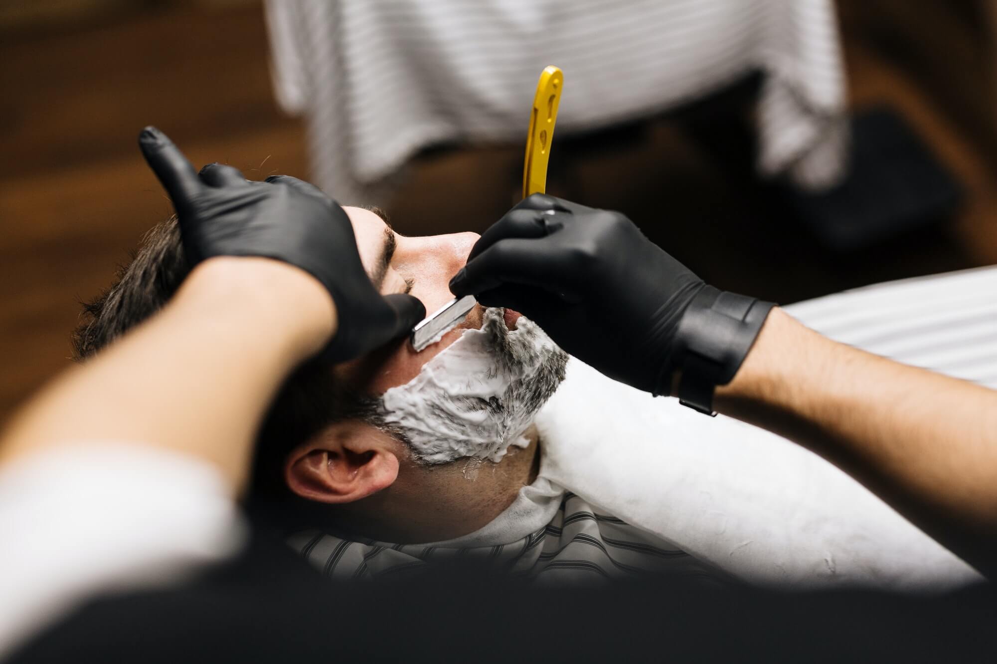 Barbero realizando un afeitado clásico a navaja a un cliente en The Original Barber Shop.